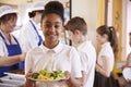 Black schoolgirl holds a plate of food in a school cafeteria Royalty Free Stock Photo