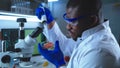 Black scientist inspecting tomato under microscope