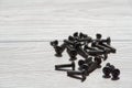Black screws are scattered on wooden background Royalty Free Stock Photo