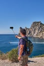 Black Sea coast, Crimea. An Asian elderly man takes photos over the background of the Blue Bay on the tourist route Golitsyn trail Royalty Free Stock Photo