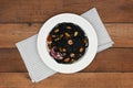 Black seafood pasta in white plate on rustic background.