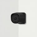 A black security camera mounted on a white wall. The camera has a rounded, Royalty Free Stock Photo
