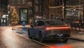 Black sedan driving along an asphalt road in the evening, illuminated by street lights