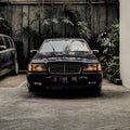 Black sedan parked in the outdoor parking lot with reflections