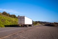 Black semi truck with trailer drive on straight road with green