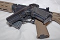 A black semiautomatic 40 caliber handgun on top of a black and brown 223 caliber AR-15