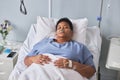 Black senior woman laying on bed in hospital room with IV support Royalty Free Stock Photo