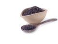 Black sesame in wooden spoon with oval light brown bowl isolated