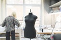 Black sewing dummy on the background of a seamstress workplace and a girl who works