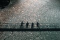 black shadows of four people standing side by side leaning over the railing of a suspension bridge over the clear Royalty Free Stock Photo