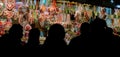 Black shilouettes of people in front of the gingerbread heart stall at the Braunschweig Christmas Market at night