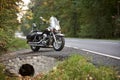 Black shiny high-speed motorcycle parked on empty narrow country roadside on sunny summer day. Royalty Free Stock Photo