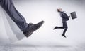 Black shoe kicking small man Royalty Free Stock Photo