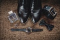 Black shoes, black belt, black watch, black butterfly, cufflinks and perfume on a brown background with sacking