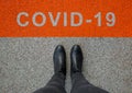 Black shoes standing on the asphalt concrete floor with orange line. Feet shoes walking in outdoor. Coronavirus in the world. Royalty Free Stock Photo