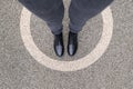 Black shoes standing in white circle on the asphalt concrete floor. Comfort zone or frame concept. Feet standing inside Royalty Free Stock Photo