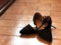 Black shoes on tiled floor across wooden furniture close-up. Female shoes. Female fashion