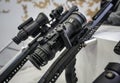 Black shooting scope optics mounted on metal bar displayed at weapons exhibition fair, closeup detail to adjustment knobs