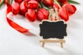 A black sign against a background of red tulips on white table. The concept of Mother`s Day. Copy space Royalty Free Stock Photo