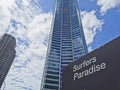 Black sign board with white text `Surfers Paradise` in front of high-rise skyscraper hotels in sunny day