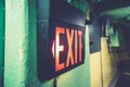 Black sign with red light with [EXIT] written on it on the wall