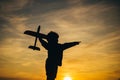 Black silhouette of cute happy child running at countryside and holding toy plane in hand. Happy kid on summer field Royalty Free Stock Photo