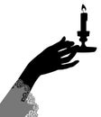 Black silhouette of female hand holding a candlestick with burning candle