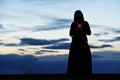 Black silhouette of a girl in a hoodie with a candle in her hands