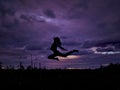 Black silhouette of a girl with long hair on a background of sunset. Violet sunset