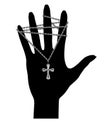 Black silhouette of a hand with a chain on the fingers and with a catholic cross on a chain on the palm isolated on white