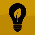 Black silhouette of a light bulb with a green leaf inside on a textured mustard yellow background Royalty Free Stock Photo