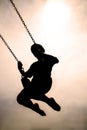 Silhouette of Child Swinging on PLaygroung Swingset