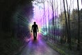 Black silhouette of a man with luminous rays of energy in a dark forest on the road among the trees, the concept of aura, living Royalty Free Stock Photo