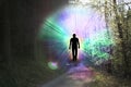 Black silhouette of a man with luminous rays of energy in a dark forest on the road among the trees, the concept of aura, living Royalty Free Stock Photo