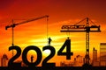 Black silhouette staff works as a to prepare to welcome the new year. Construction cranes set numbers 2024. Royalty Free Stock Photo