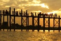 Black silhouette of teakwood U Bein Bridge and walking people on background of orange cloudy sky at sunset time, Burma
