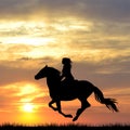 Black silhouette of woman riding a horse at sunrise