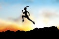 Black silhouette of woman running forward on the rocks.