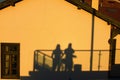 Black silhouette of a young couple on the yellow wall of building. Shadow of two persons on the wall. Beautiful sunset time