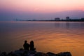 Black silhouettes, couples sitting by the sea in the evening.