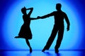 Black silhouettes of dance partners performing Argentine tango. Man and woman are dancing choreography elements on blue Royalty Free Stock Photo