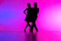 Black silhouettes of pair of ballroom dancers performing elements of Argentine tango against blue pink gradient Royalty Free Stock Photo