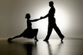 Black silhouettes of pair of ballroom dancers performing elements of Argentine tango. Man and woman are dancing on gray Royalty Free Stock Photo