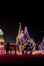 Black silhouettes of people amid the bright lights of Christmas street scenery. Night shooting of urban landscape