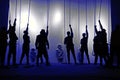Black silhouettes of people with ropes in their hands at the theater, Shadow play