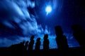 Black silhouettes of standing moais against starry blue sky in E