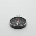 Black and silver compass with a circular design on a light gray background. The Royalty Free Stock Photo