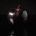 Black single realistic shiny apple with water drops on dark background. AI generative illustration Royalty Free Stock Photo