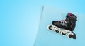 Black single row roller skates on a blue background. Stylish roller skates on blue background, top view