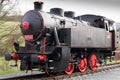 Black single steam locomotive with red wheels. Renovated engine